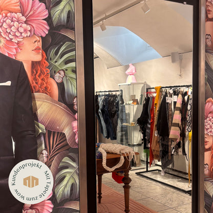 Spiegel vor Tapete mit Frauenkopf und rosa Blüten in Kleiderboutique
